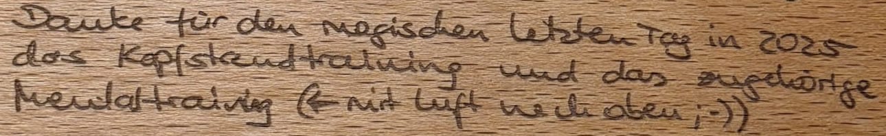 Derselbe Satz im Holz, dieselben drei Zeilen, dieselben Umbrüche.