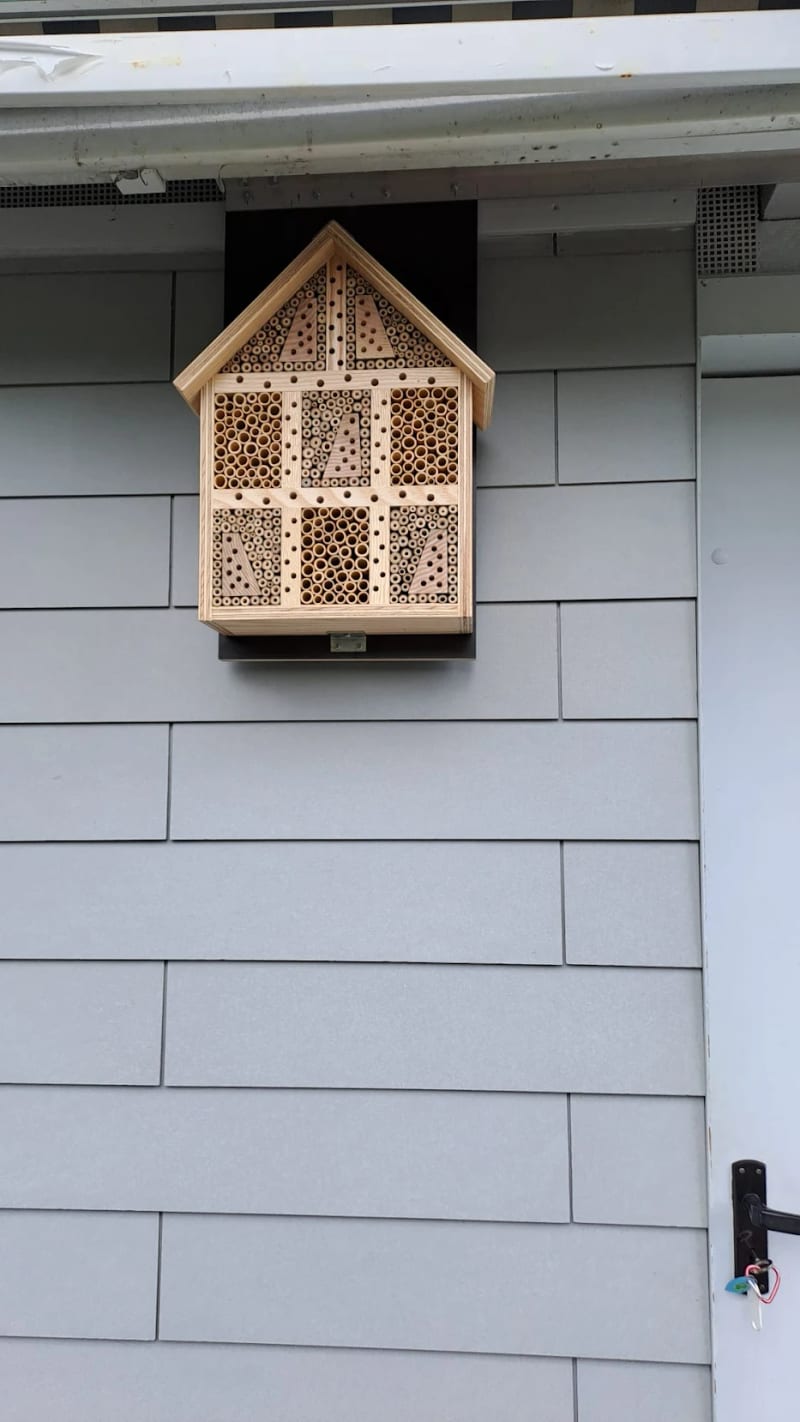 Das Insektenhotel an der Hauswand unter dem Dachvorsprung
